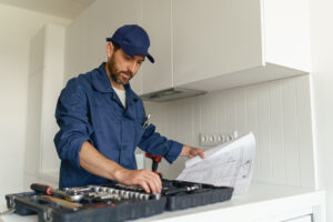Male worker with toolbox standing on home kitchen background . High quality photo